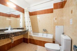 a bathroom with a toilet and a sink and a tub at Livadia Beach Suite in Tílos