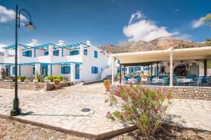 a white house with blue windows and a patio at Livadia Beach Suite in Tílos