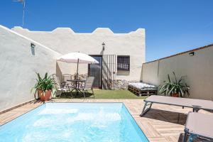 a patio with a pool and a table and an umbrella at Casa Dorca 1 in Conil de la Frontera