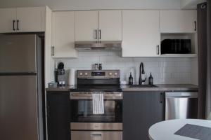 a kitchen with white cabinets and a stove top oven at Appart'hôtel Vivéo - Par Aneyro in Quebec City +32 photos