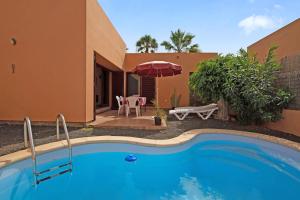a villa with a swimming pool in front of a house at La Palmera de la Oliva in La Oliva