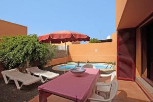 a table and chairs and an umbrella and a pool at La Palmera de la Oliva in La Oliva