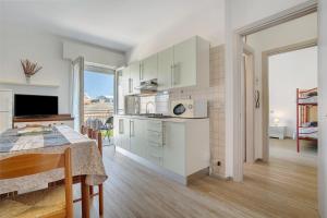 a kitchen with white cabinets and a table and a dining room at Villa Trentina in Lido di Jesolo