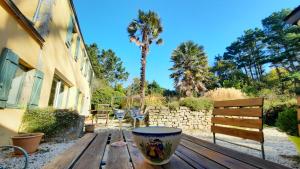 a wooden table with wine glasses and a palm tree at La maison jaune - 3ch - 6pers in Loctudy