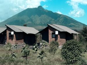 an old brick house with a mountain in the background at Volcanoes Over View Safaris & Camp in Nyarugina
