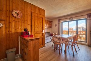 a dining room with a table and a couch at Studio Alpe d'huez in LʼHuez