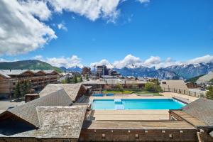 a view of a resort with a swimming pool and mountains at Studio Alpe d'huez in LʼHuez +13 photos