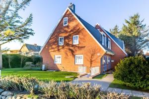 a large red brick house with white windows at Tolle Wohnung mit Sonnenbalkon in Wenningstedt