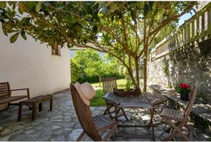 a patio with a table and chairs under a tree at Puente del Narcea 3 in Cibuyo +3 photos