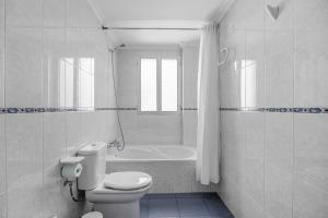 a white bathroom with a toilet and a bath tub at Chipiona Centro y Playa in Chipiona +25 photos