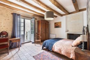 a bedroom with a bed and a desk and a window at Le Logis de Cléré in Cléré-les-Pins