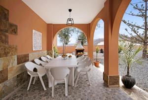 an outdoor dining room with a white table and white chairs at Abundia House in Caleta De Fuste