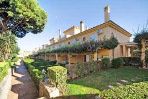 a large house with bushes and trees in front of it at Chalet Cormoran in Chiclana de la Frontera