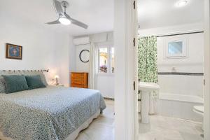 a white bedroom with a bed and a bath tub at Chalet Cormoran in Chiclana de la Frontera +17 photos