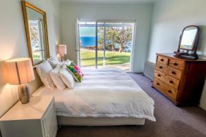 ein Schlafzimmer mit einem Bett, einer Kommode und einem Fenster in der Unterkunft Antechamber Bay Retreats in Penneshaw