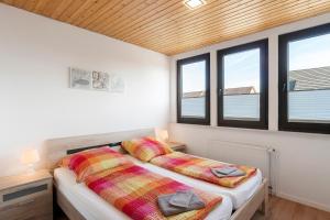 two beds in a room with two windows at Gästehaus Vogel in Horumersiel
