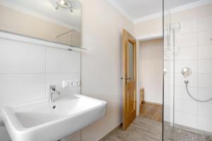 a white bathroom with a sink and a shower at Wohnung Hochstaufen in Inzell