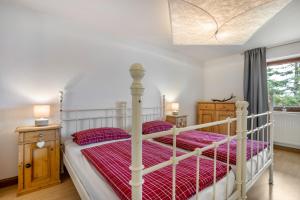 a bedroom with a white bed with a red comforter at Ferienwohnung Silvia in Roßhaupten