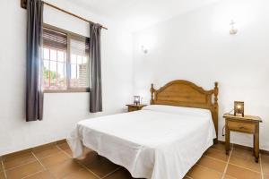 a bedroom with a white bed and a window at El Madroño in El Palmar