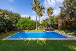 a swimming pool in a yard with palm trees at Villa Cala Bona in Cala Bona