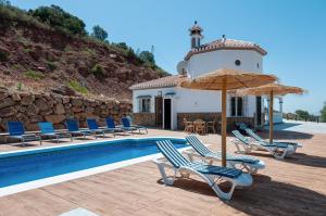 a villa with a swimming pool with chairs and an umbrella at Sunset El Tejar in Almogía