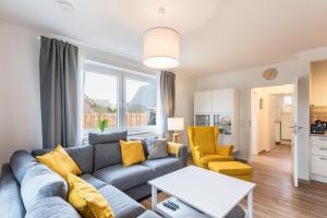 a living room with a blue couch and yellow chairs at Haus Hein Mück in Norden