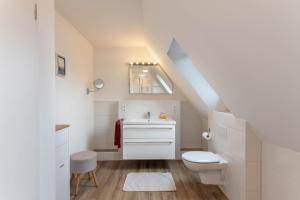 a white bathroom with a toilet and a sink at Haus Hein Mück in Norden