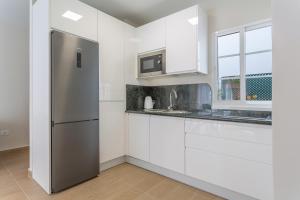 a kitchen with white cabinets and a stainless steel refrigerator at Puerto Playa 3 in Puerto del Rosario