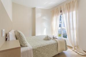 a white bedroom with a bed and a window at Puerto Playa 3 in Puerto del Rosario
