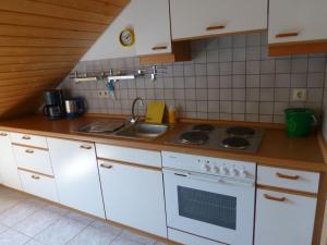 a kitchen with white cabinets and a sink and a stove at Moorwiesenhof in Ostrach