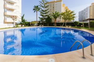 a large blue swimming pool with buildings in the background at Gandiazar Beach in Playa de Gandia