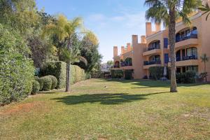 a large building with palm trees and a yard at Apartamento T2 Vilasol Morgadinho in Vilamoura