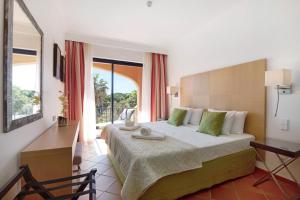 a bedroom with a bed and a desk and a window at Apartamento T2 Vilasol Morgadinho in Vilamoura +25 photos