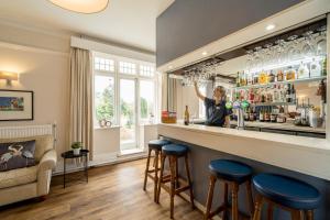 a woman standing behind a bar with blue stools at Northfield Hotel in Minehead