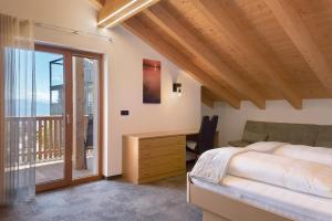 a bedroom with a bed and a desk and a balcony at Living Lerchna - Schöne Aussicht 2 in Maranza