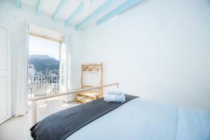 a white bedroom with a bed and a large window at Marina 48 Seafront Apartment in Port de Soller