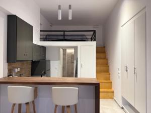 a kitchen with white cabinets and white stools at Kamara Studios in Alinda