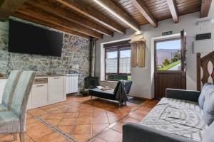 a living room with a tv on a stone wall at La Picarota in Pajares