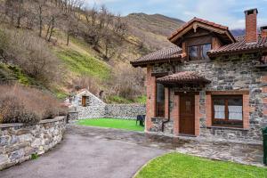 a brick house with a stone wall and a yard at La Picarota in Pajares