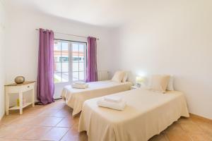 two beds in a room with purple curtains at Casa Nelson e Esperanca in Vila Nova de Milfontes