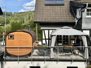 a building with a barrel and an umbrella on a patio at Bergisch Resort Helle in Lindlar