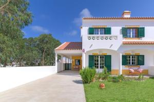 a white house with green shutters and a yard at Casa Nelson e Esperanca in Vila Nova de Milfontes