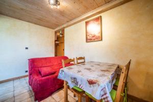 a living room with a table and a red couch at Studio Chénives - Morzine in Morzine