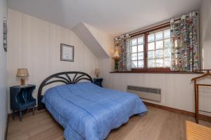 a bedroom with a blue bed and a window at Maison proche de la mer in Arzon