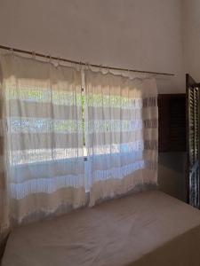 a room with a large window with a curtain at Casa Medrado in Porto Seguro