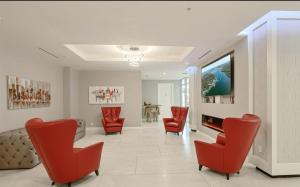 a living room with red chairs and a flat screen tv at Single, Double or Quad Oceanview Studios - Direct Beach Access, Oceanfront Pool & Tiki in Daytona Beach Shores