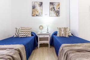 two beds in a room with blue sheets and a table at NURAS - Casa IAIA Alghero city center in Alghero