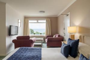 a hotel room with a bed and chairs and a window at Northfield Hotel in Minehead