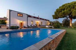 a house with a swimming pool in front of a house at Villa Rodrigues in Boliqueime