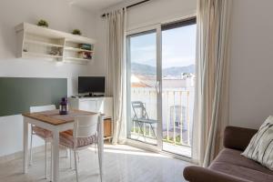 a living room with a table and a large window at Apartamento Corazón de Nerja in Nerja